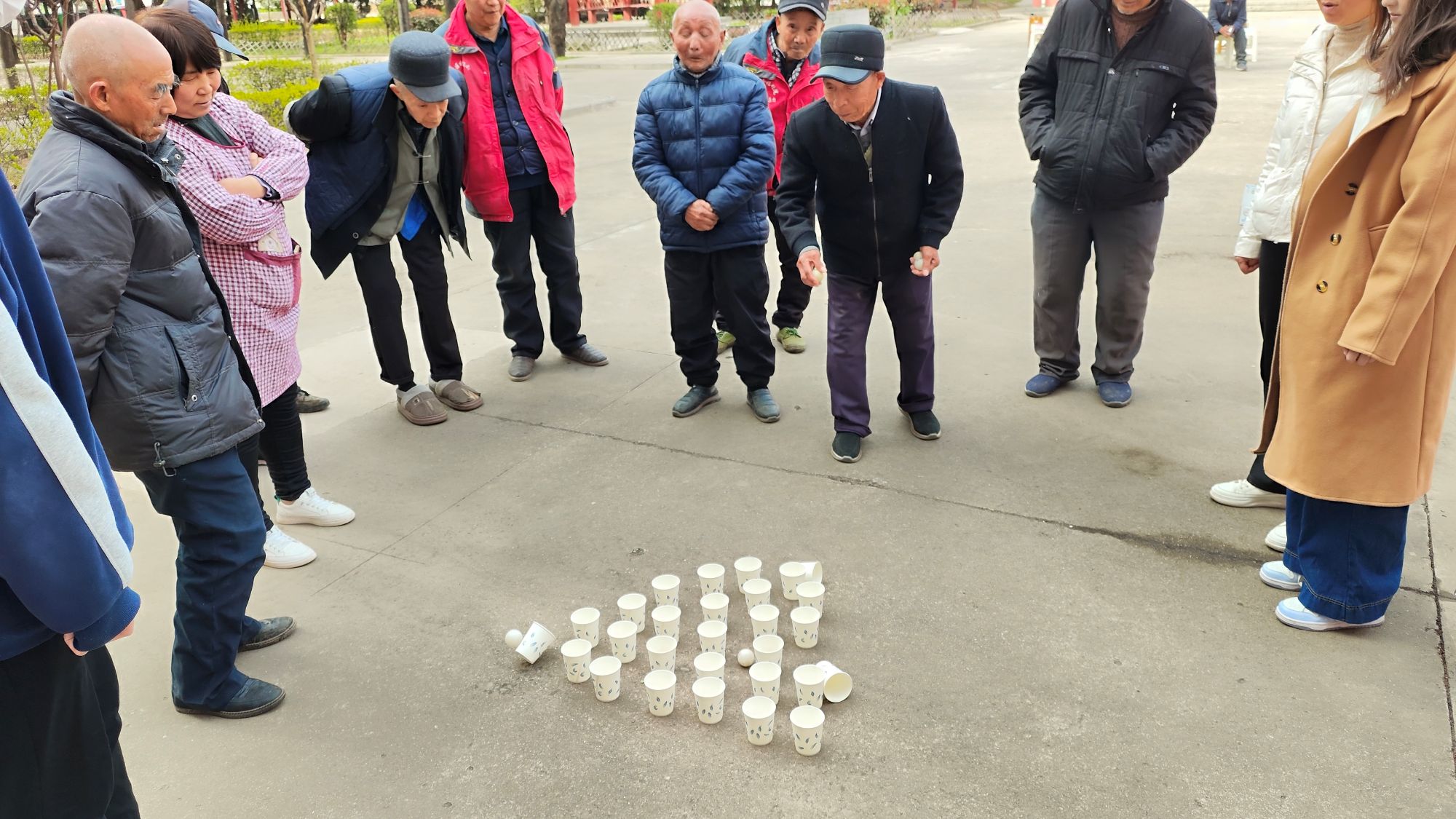 老人们进行乒乓球投纸杯游戏.jpg
